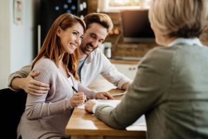 Asesoramiento profesional de una agencia de seguros a una pareja mientras revisan una póliza de seguros