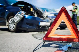Escena de accidente de tránsito con un triángulo de seguridad en primer plano, ilustrando la relevancia de tener un seguro de autos en Puerto Rico para recibir asistencia y cobertura.