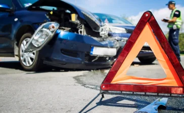 Escena de accidente de tránsito con un triángulo de seguridad en primer plano, ilustrando la relevancia de tener un seguro de autos en Puerto Rico para recibir asistencia y cobertura.
